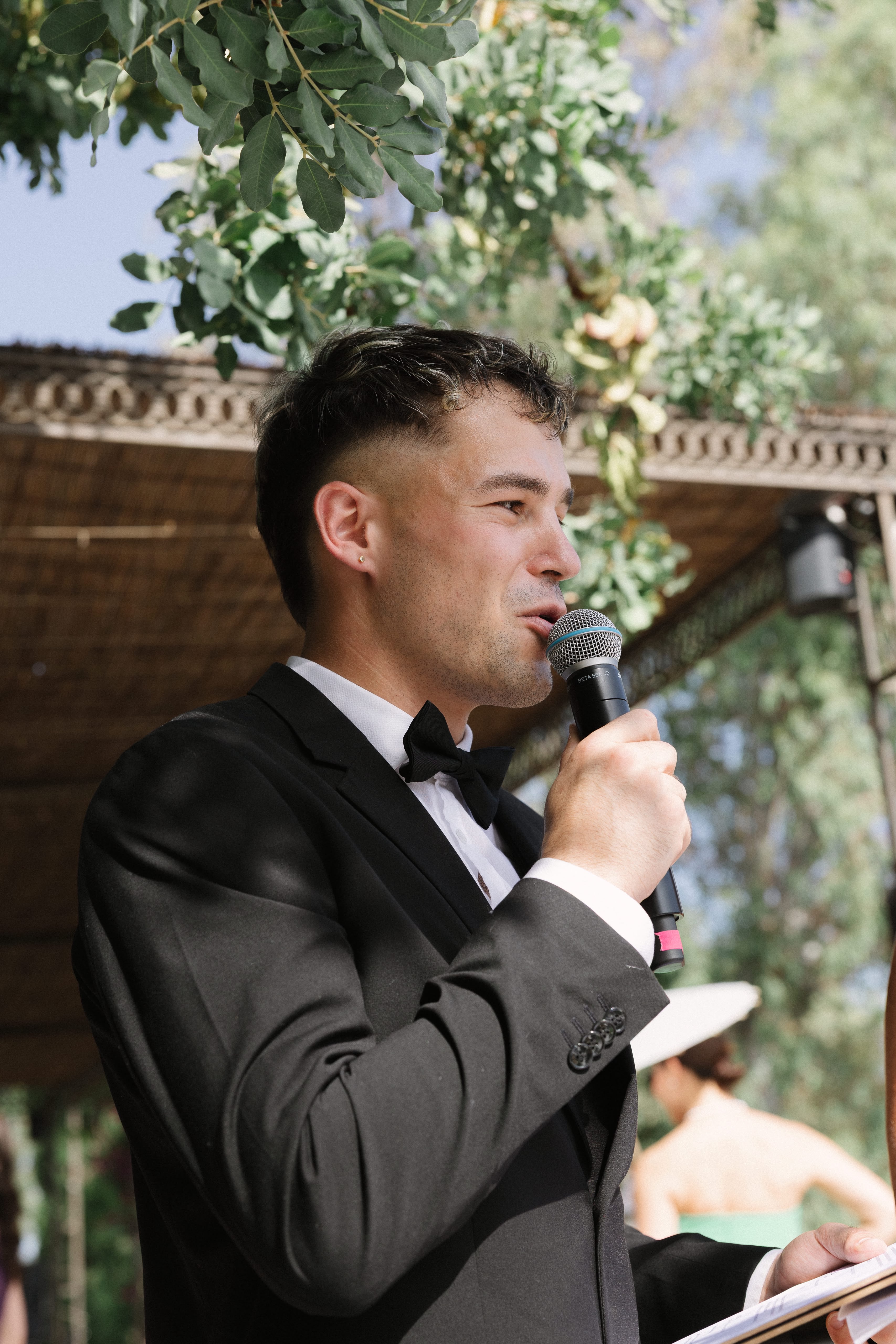 Vova speaking into a microphone at Christina and Arthur’s outdoor wedding