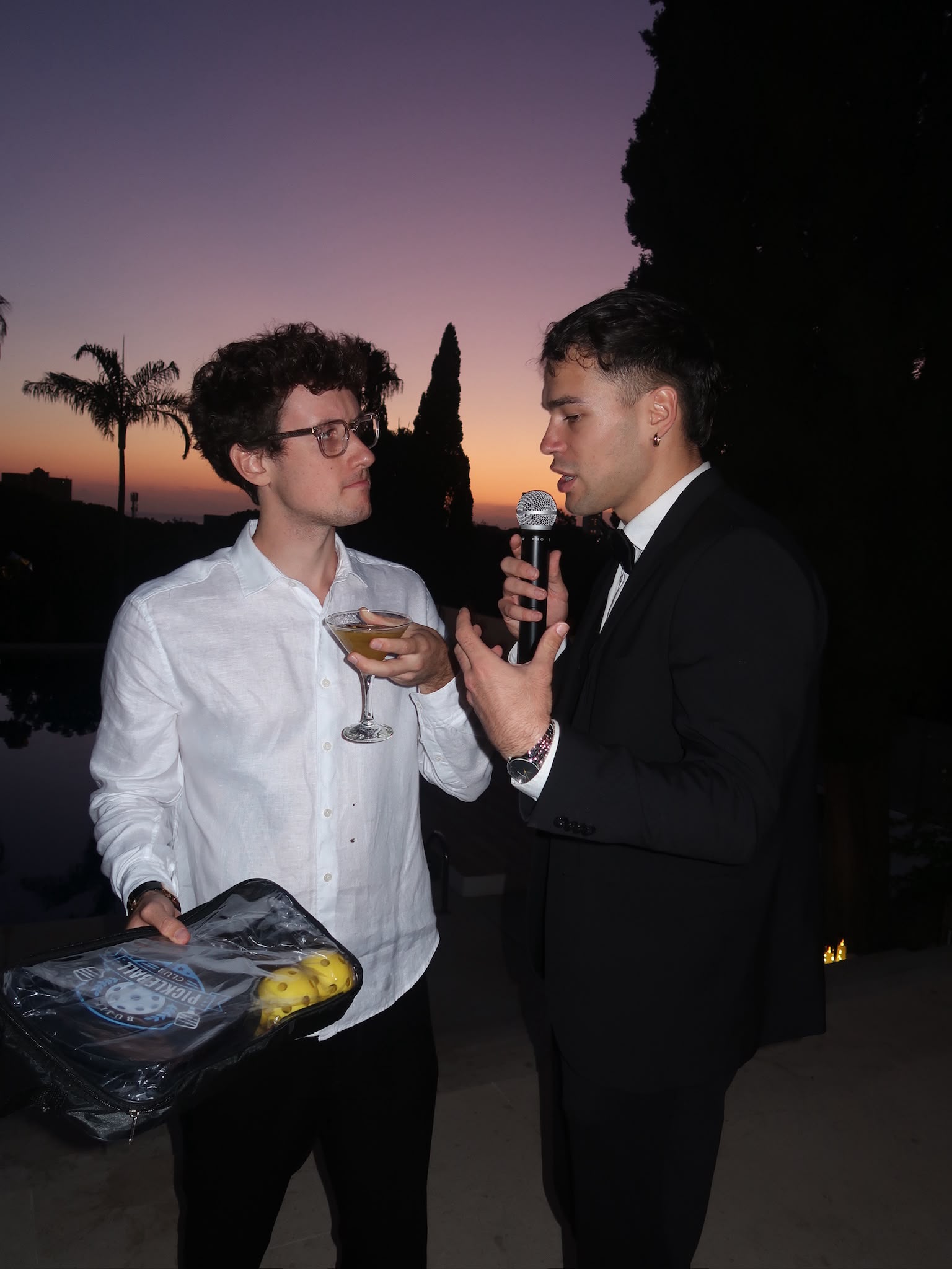 Vova explaining a party game to a guest at sunset